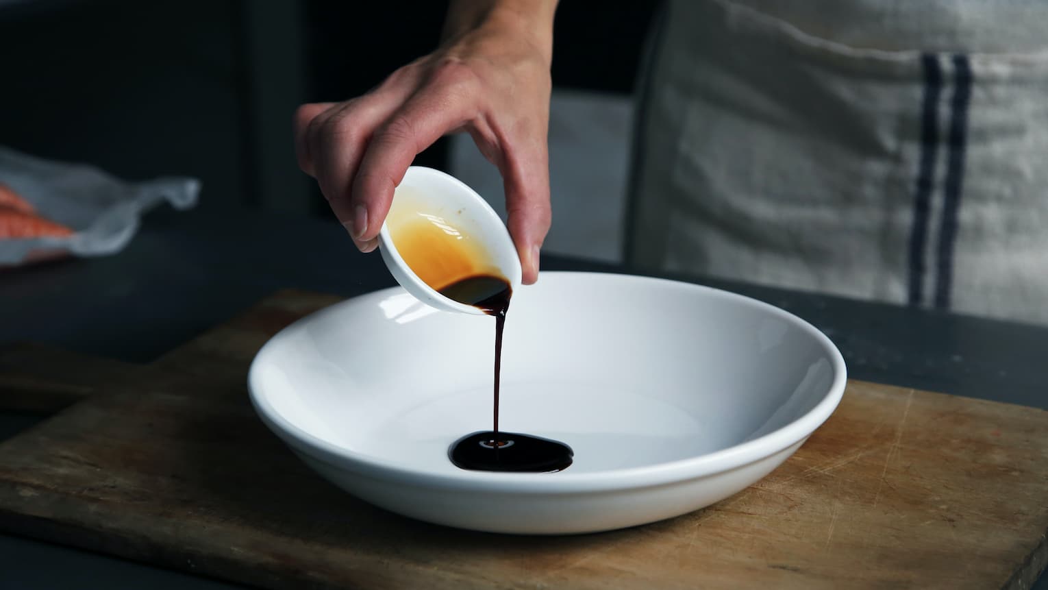 A chef pouring oyster sauce into a bowl